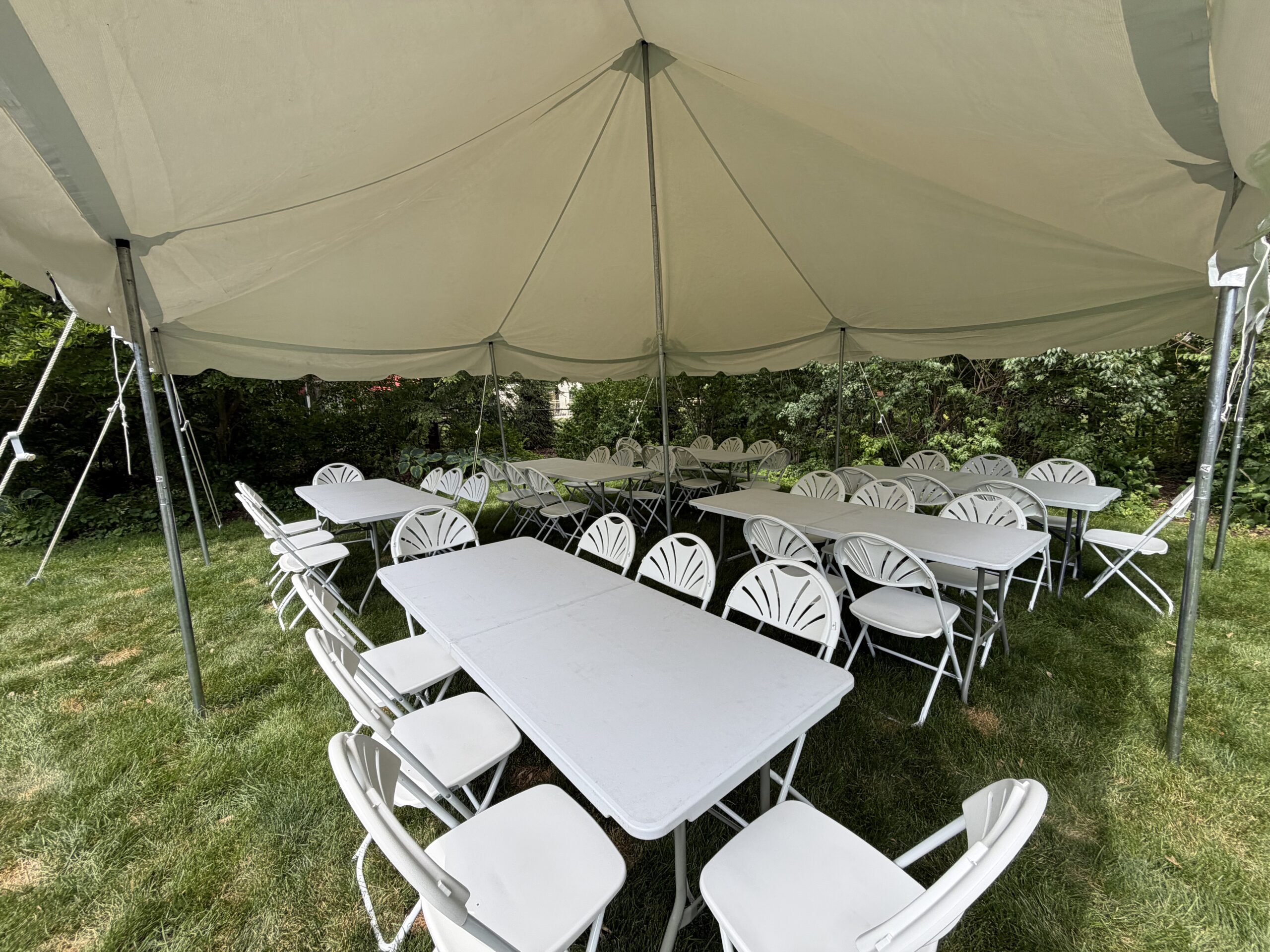 Pole tent rental with long tables and white chairs in Oakland County Michigan backyard